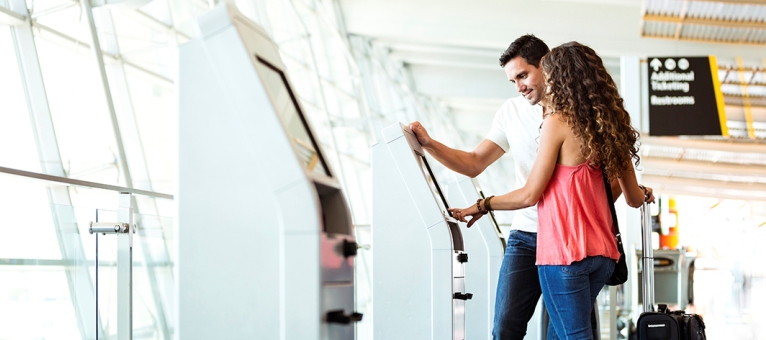 couple in airport at check in kiosk couple in airport at check in kiosk